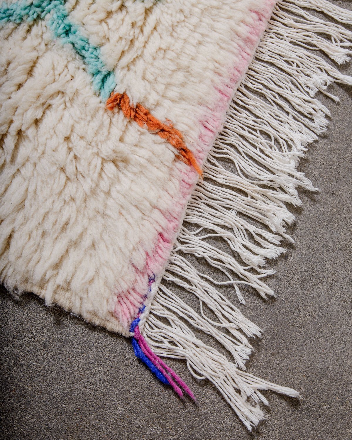 Corner of cream Azilal rug with white cotton tassels.